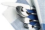 Arrangement of Silverware with Table Knife, Spoon, Fork and Dessert Fork under Blue Napkin closeup