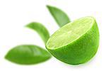 Half of fresh lime and of-focus green leaf on backdrop . Placed on white background. Close-up. Studio photography.