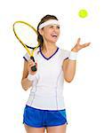 Smiling female tennis player throwing ball up