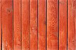 Part of vertical ancient wooden fence painted in red. Fine sunny weather