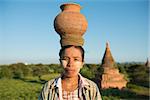 Portrait of Asian traditional farmer carrying clay pot on head going back home, Bagan, Myanmar
