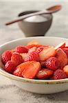 Close-up of Bowl of Strawberries and Raspberries with Bowl of Sugar in Background, Studio Shot