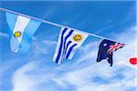 Uruguayan, Argentinian, Australian, and Japanese flags against blue summer sky