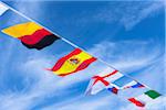 German, Spanish, English, Slovakian, and Italian flags against blue summer sky