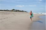 Mature Man Walking down Beach with Surfboard, USA