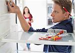 Electrician working on fridge in home