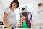 Pregnant mother helping daughter with homework