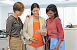 Pregnant businesswoman showing colleagues sonogram