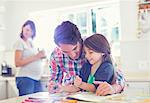 Father helping daughter use coloring book