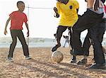 Boys playing soccer together in dirt field