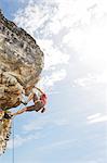 Climber scaling steep rock face