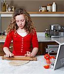 Girl rolling dough in kitchen