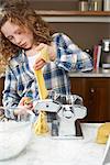 Girl rolling pasta dough in kitchen