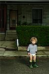 Boy Standing on Neighbourhood Street in Diaper and Rubber Boots