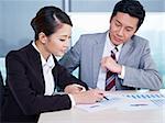 asian business executives discussing business in office; focus on the woman.