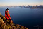 Young man on the top of mountain Festvagtinden with picturesque scenery of chain of Lofoten islands, Norway