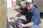 Mechanic using a tire iron to remove lug nuts from an automobile tire.