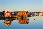 Typical red rorbu huts with sod roof in town of Reine on Lofoten islands in Norway lit by midnight sun