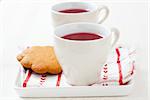 Two cups of Christmas mulled wine and gingerbread biscuits on plate on white background