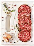 Delicious salami with thyme and spices on an old white board.