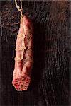 Hanging salami sausage on an old wooden board.