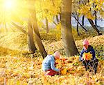 Happy family (mother with daughter) in golden evening maple autumn park and sunshine behind the tree foliage