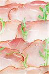 Prosciutto slices and arugula background. Shallow dof