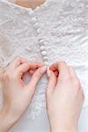 hands of girls help to the bride to button wedding dress