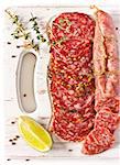 Variety of salami and spices on a white cutting board.