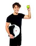 Happy fit guy with weighing scale and green apple. Isolated on white background.