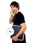 Smart boy eating green apple with scale in his other hand