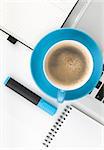 Blue coffee cup and office supplies. View from above. On white background