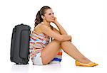 Young tourist woman with wheel bag sitting on floor