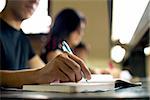 Students doing homework and preparing exam at university, closeup of young man writing in college library