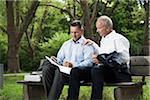 Businessmen Looking at Work on Park Bench, Mannheim, Baden-Wurttemberg, Germany