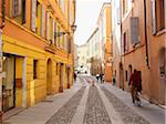 quaint cobblestone street with pedestrians and bicyclists, Modena, Italy