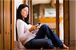 Woman sitting on the floor and sending a text message on a smart phone