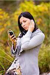 Woman wearing earbuds and listening to a smart phone outdoors