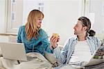 Couple On Sofa, Woman Using Laptop, Man Reading Newspaper