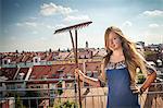 Woman On Roof Terrace Holding Garden Rake, Munich, Bavaria, Germany, Europe