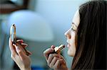 Woman putting on lipstick, looking into hand mirror, Copenhagen, Denmark