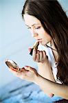 Woman putting on lipstick, looking into hand mirror, Copenhagen, Denmark