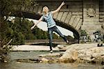 Young woman balancing on the waterfront, Munich, Bavaria, Germany