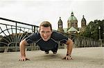 Young man doing push-ups on bridge, Munich, Bavaria, Germany