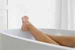 Woman relaxing in bath, low section