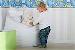 Baby boy playing with teddy bear on beanbag chair