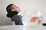 Businessman resting with neck pillow in office, side view