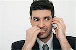 Mid-adult businessman talking on cell phone with anxious expression