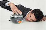 Businessman looking at goldfish in fishbowl