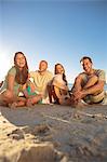 Smiling friends  sitting on the beach